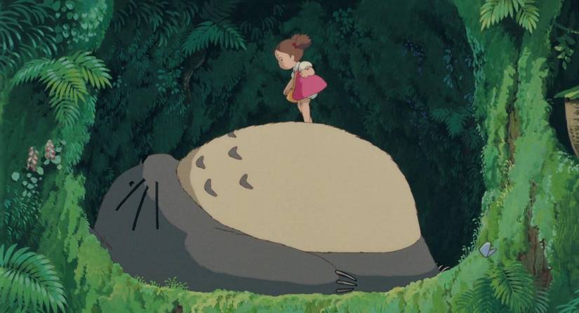 A small child stands on the tummy of a large, rotund forest creature in My Neighbor Totoro