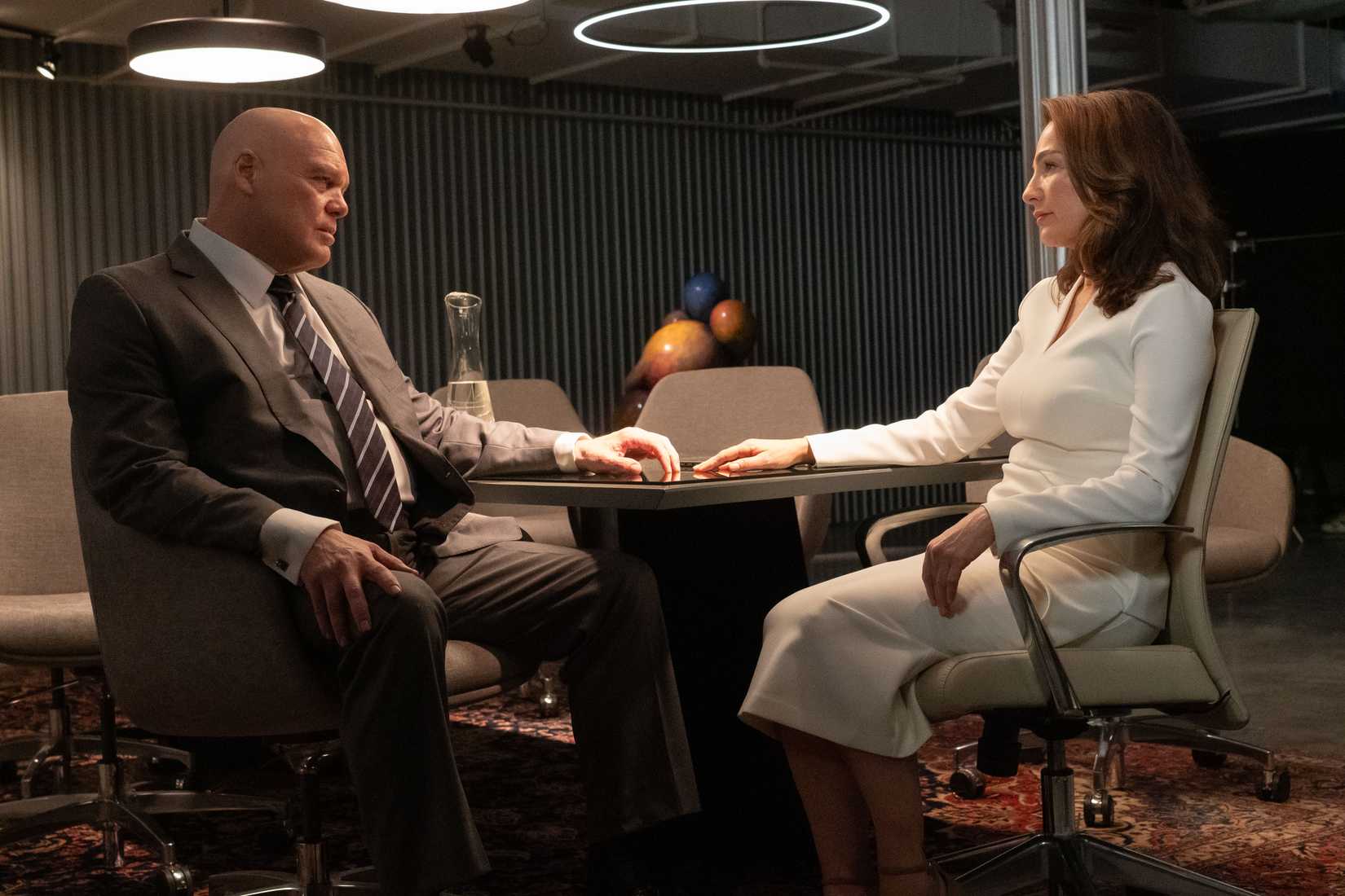 Kingpin and Vanessa are seated at a table, looking at each other, with their hands outstretched on the table and almost touching, in Daredevil: Born Again