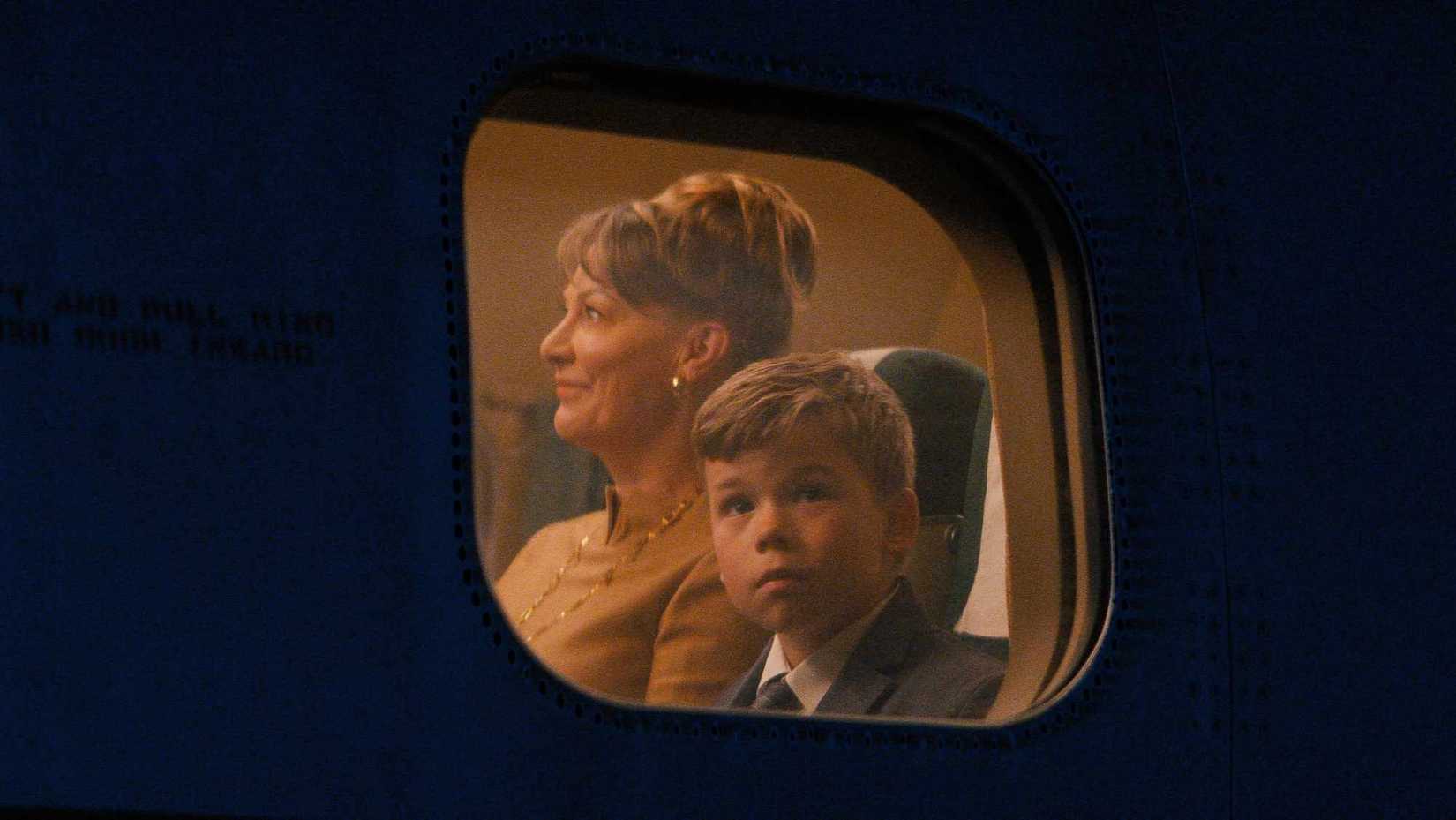 A boy sitting next to a woman, staring out the window