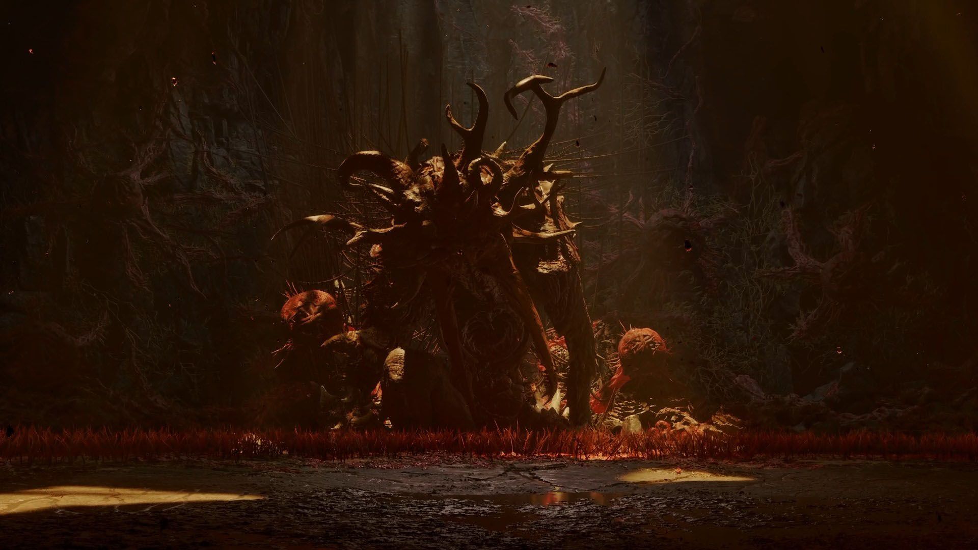 A Lovecraftian looking monster with multiple antlers protruding from its head in a dark cave with red grass in Saros.