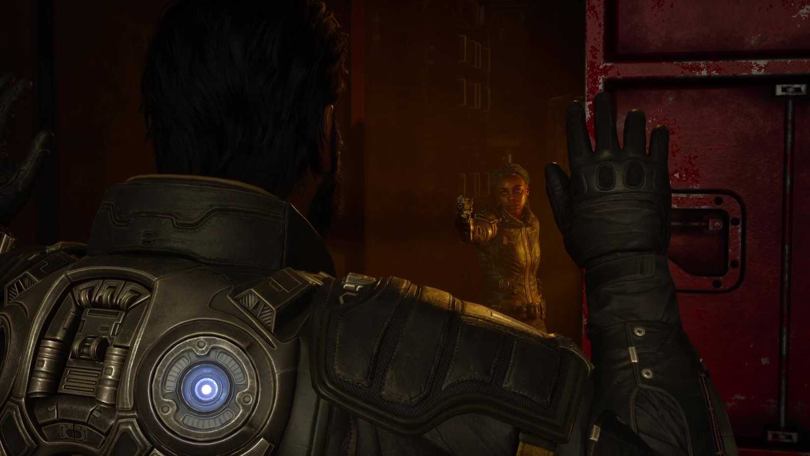 Arjun holding his hands up as Kayla points a gun at him.