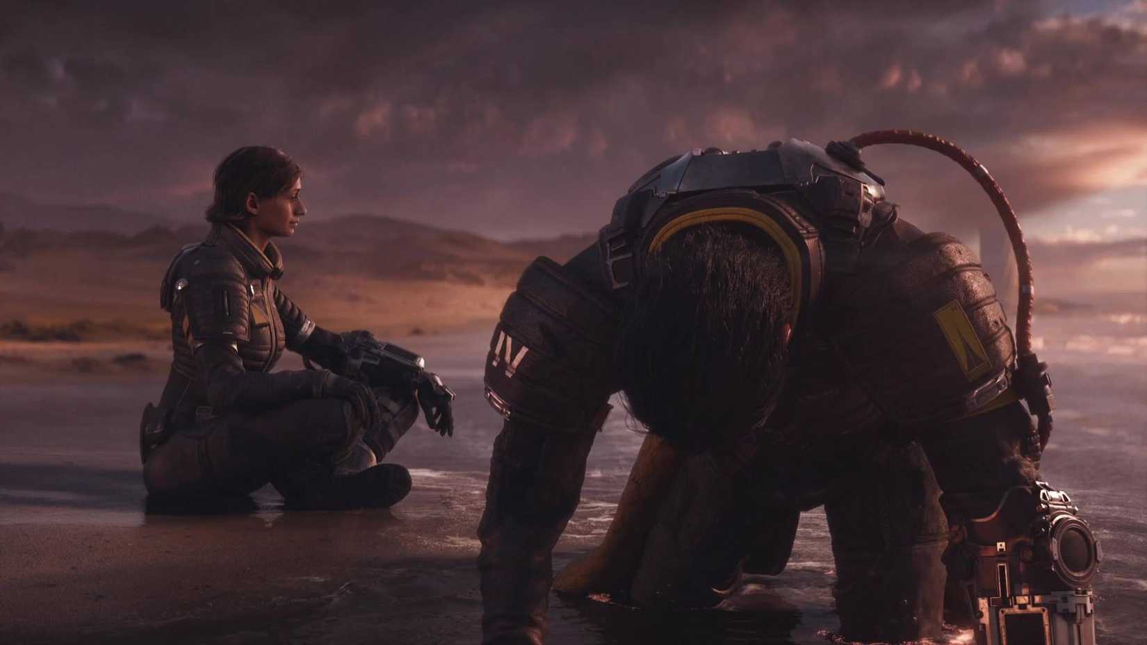 Arjun on all fours on the beach with Nitya sat cross-legged behind him.