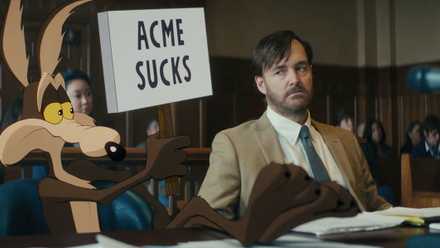 Wile E. Coyote hold a sign that reads