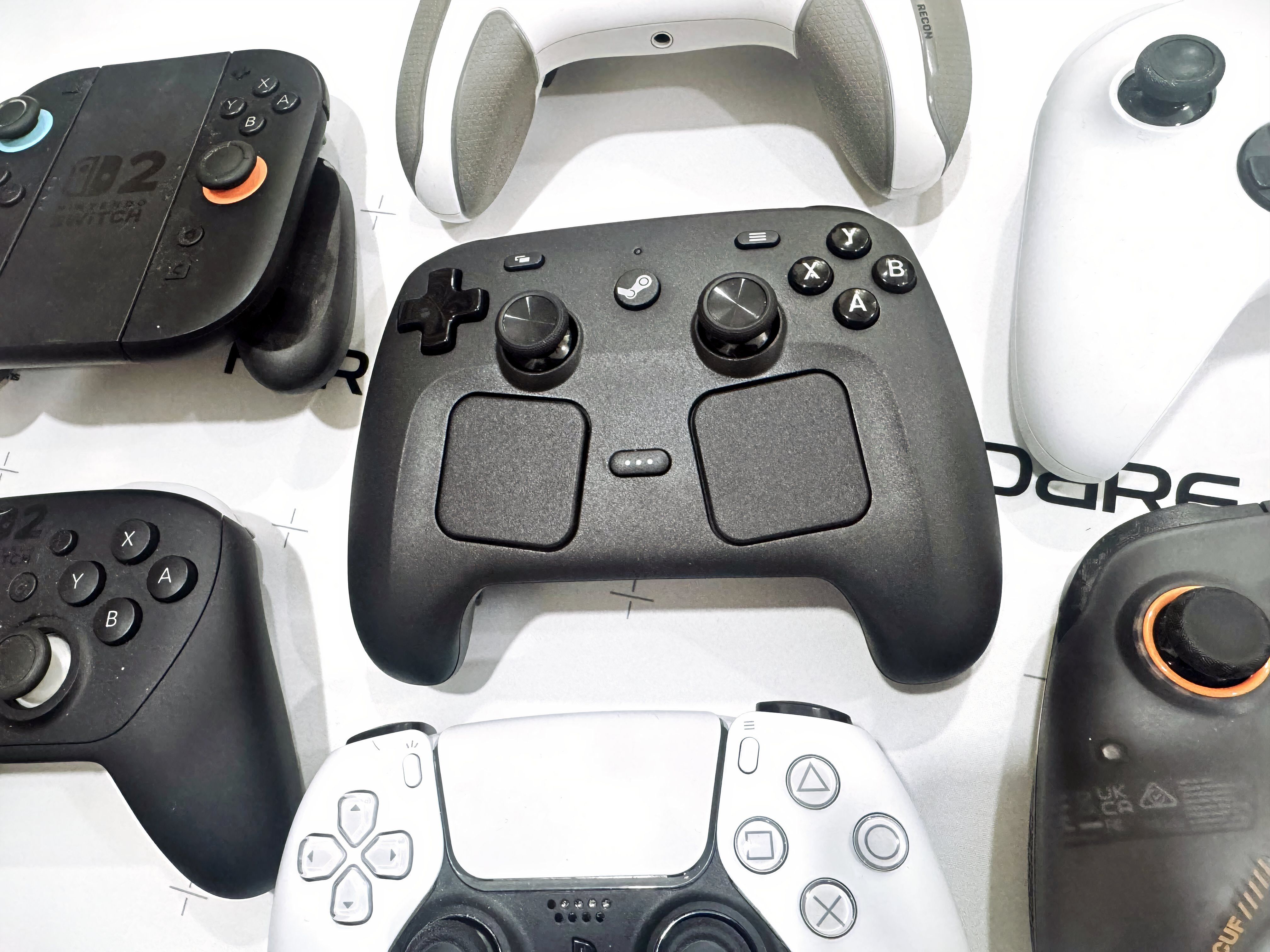 A collection of various modern gaming controllers on a desk