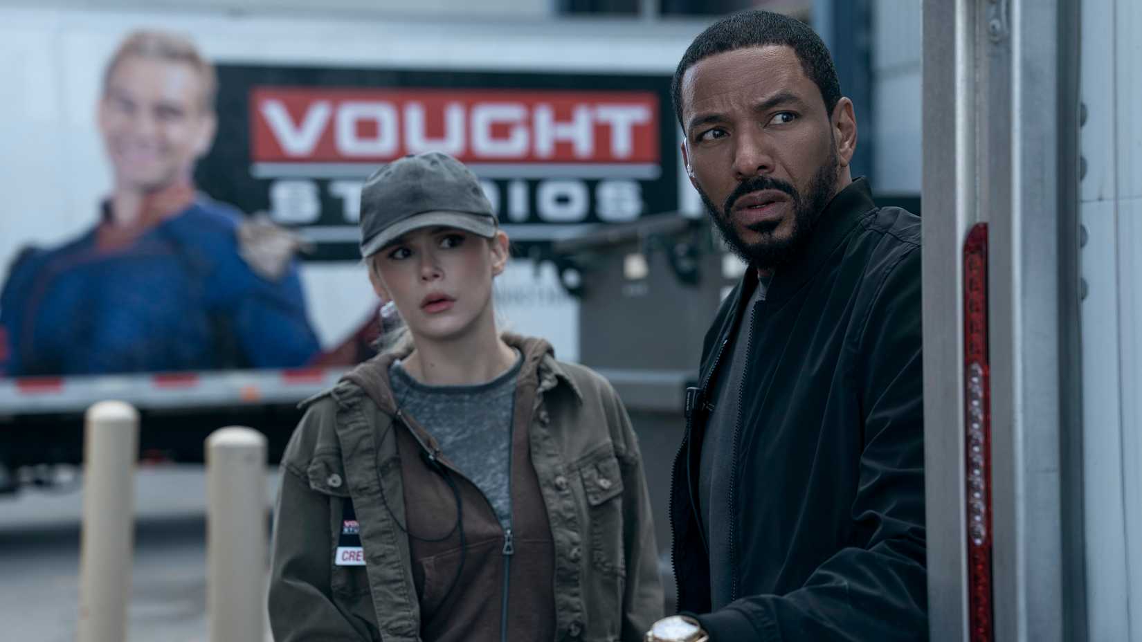 Annie January aka Starlight (Erin Moriarty) hides next to Mother's Milk (Laz Alonso) in front of a Vough Studios billboard depicting Homelander in The Boys season 5