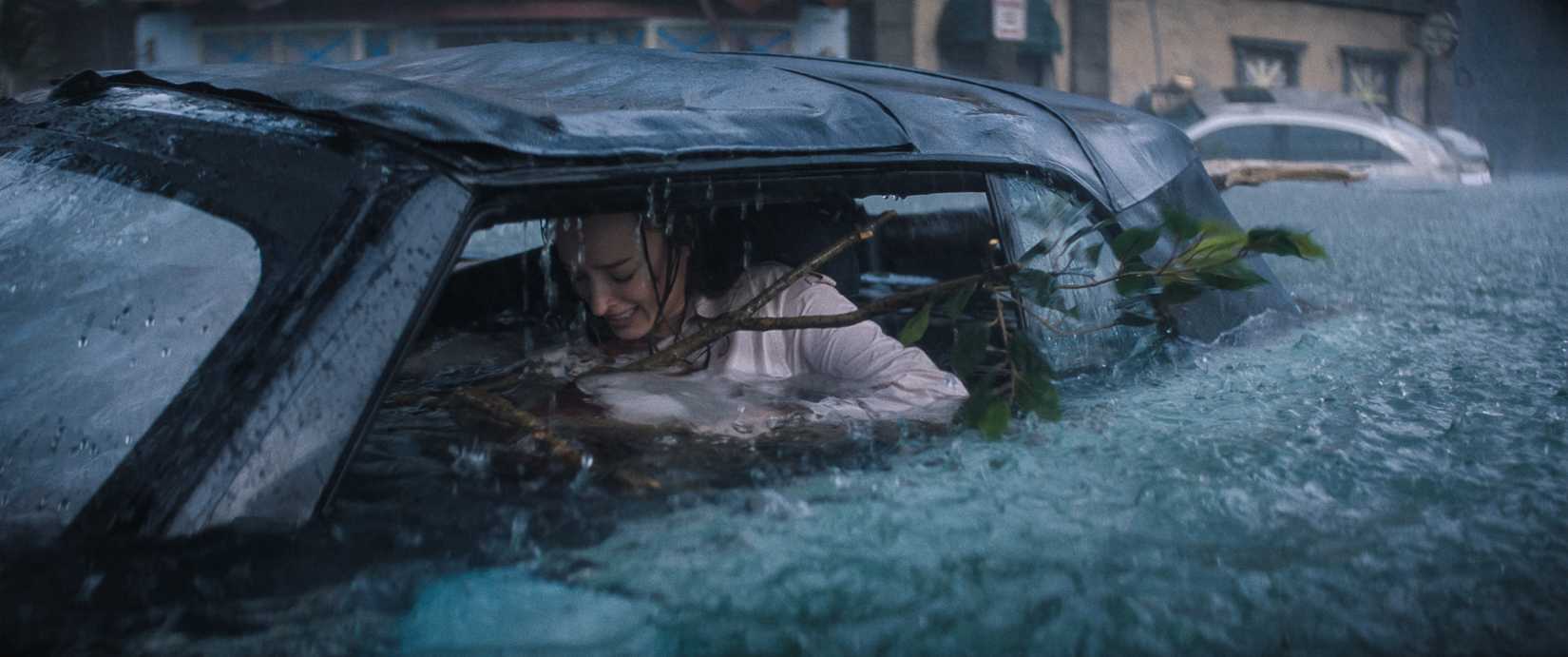 A pregnant woman (Phoebe Dyvenor) struggles to free herself from her car, where she is trapped as floodwaters rise in a scene from Thrash.