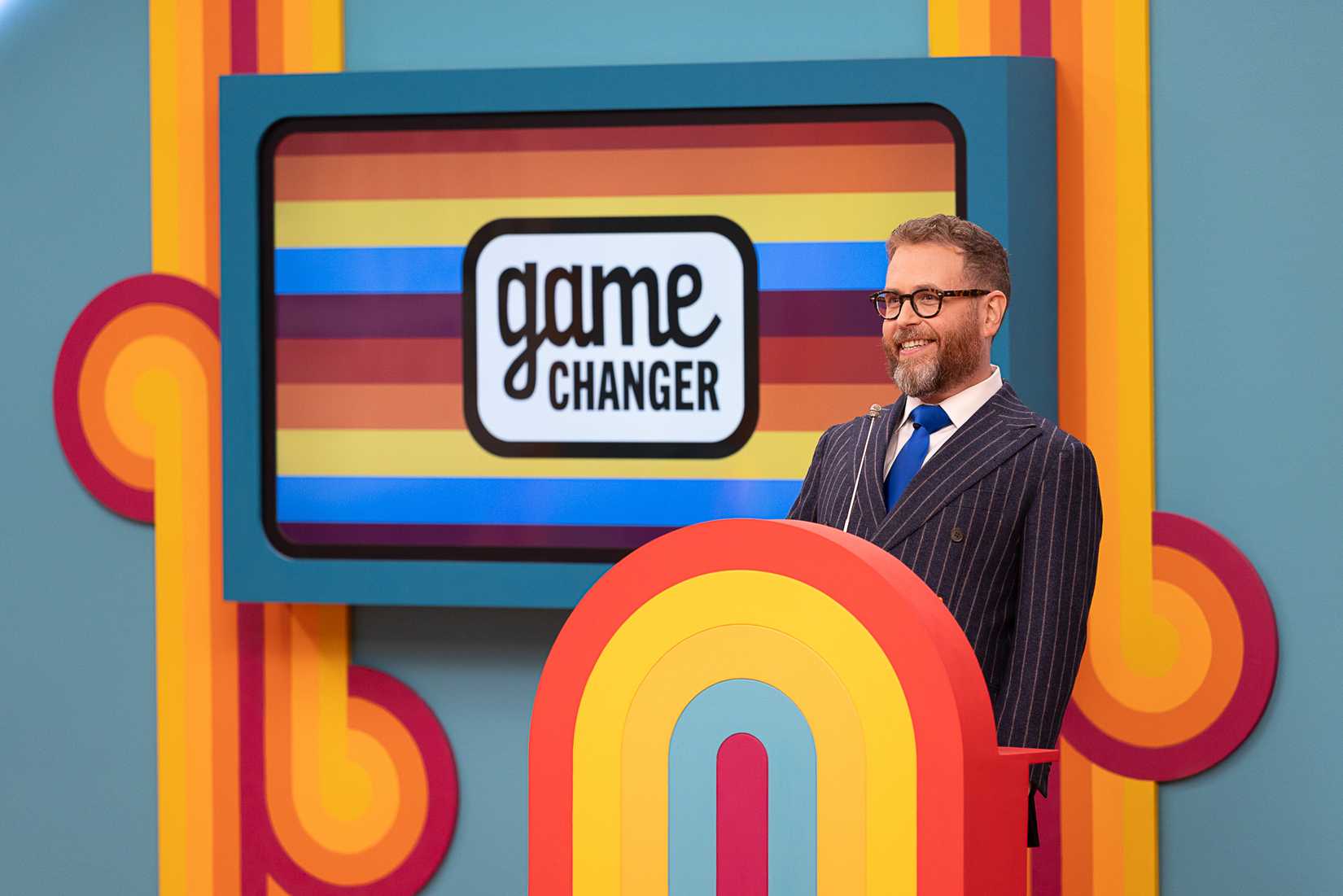 Dropout CEO Sam Reich stands at his podium on the set of Game Changer season 8