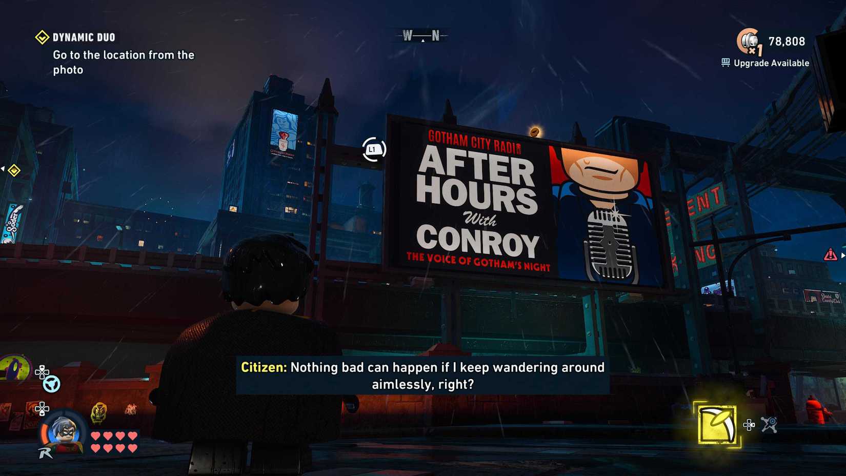 Lego Batman Legacy of the Dark Knight screenshot showing a billboard that cats as a  Kevin Conroy tribute