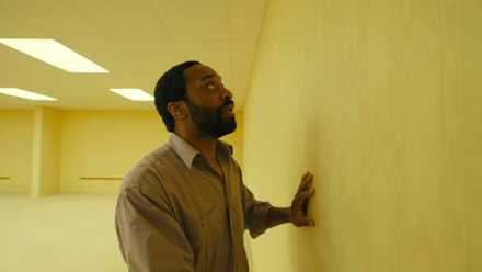 Clark (Chiwetel Ejiofor) runs his hands along a yellow wall in Backrooms