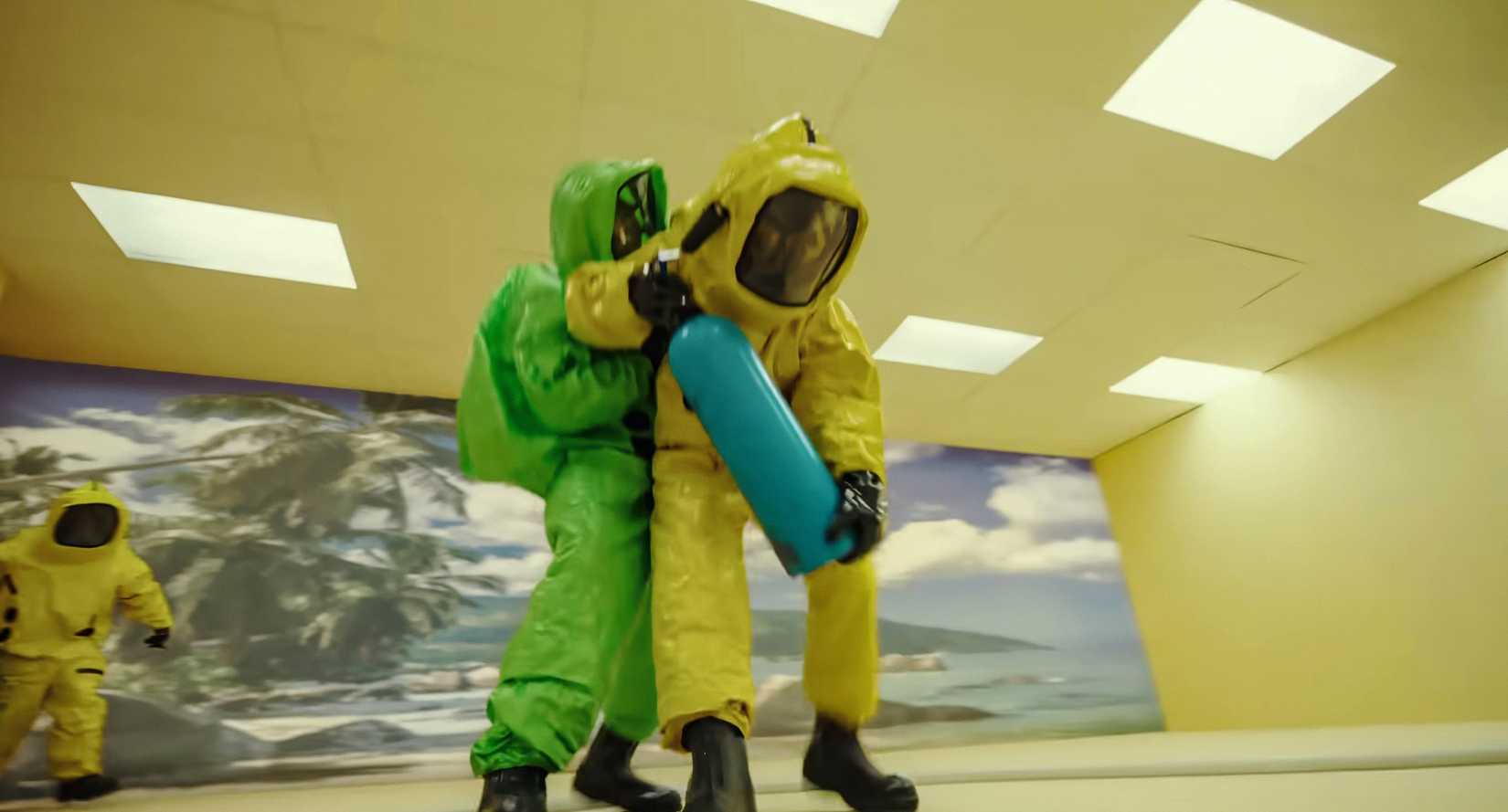 A figure in a green Hazmat suit clings to someone in a green one as they stand in a yellow-wallpapered room in Backrooms