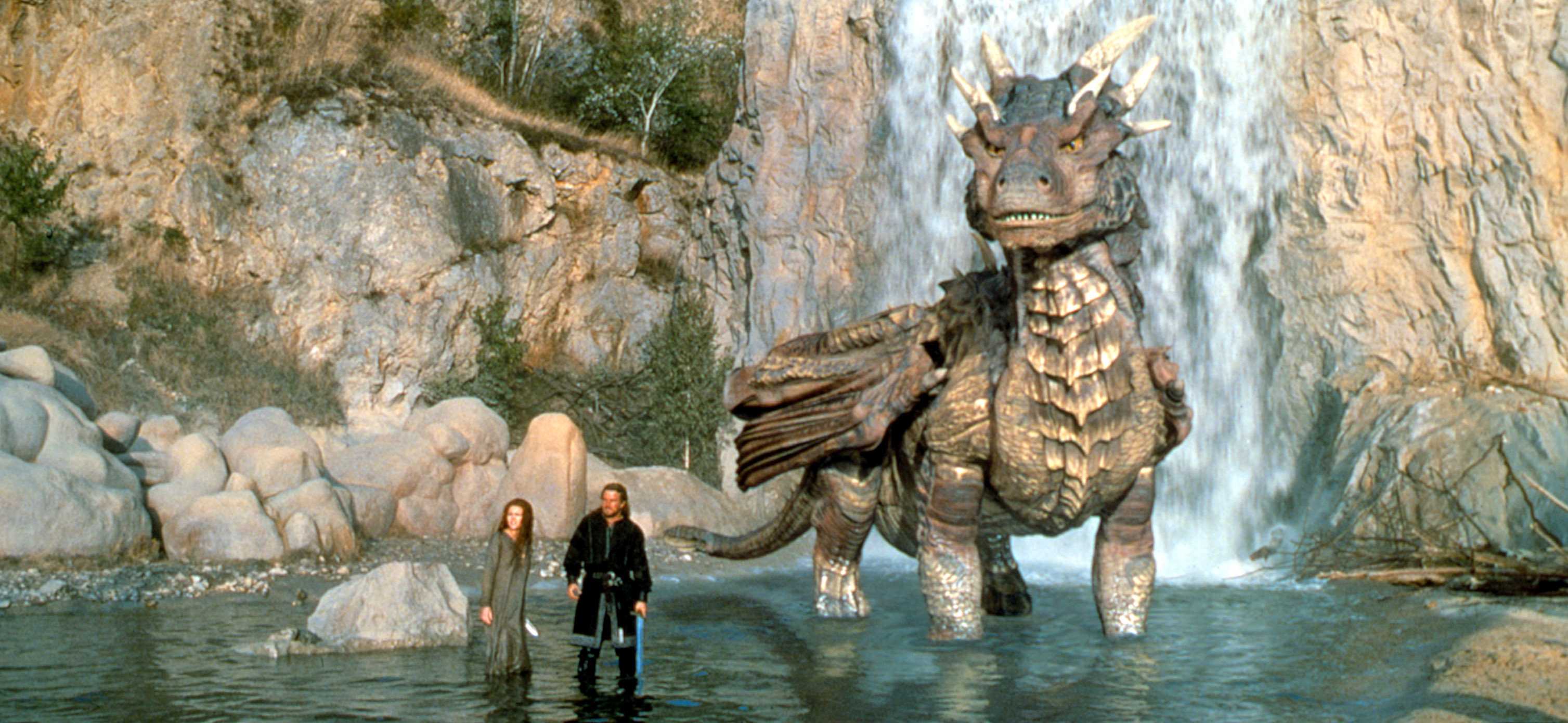 An image from Dragonheart 1996. It shows a woman and a man standing ankle deep in water. Next to them is a large dragon.