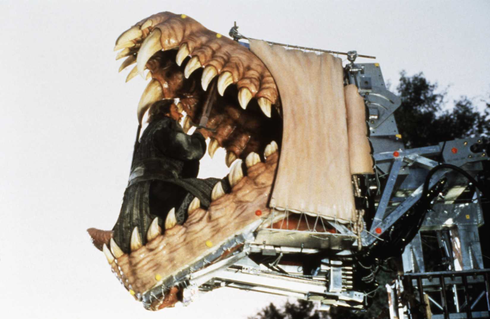 A behind the scenes image of Bowen from Dragonheart 1996. It shows Quaid, as Bowen, sitting inside an animatronic dragon head.