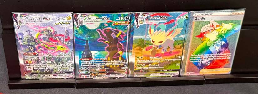 A set of 4 miscut Pokemon cards, which includes a highly-sought after Umbreon VMAX card.