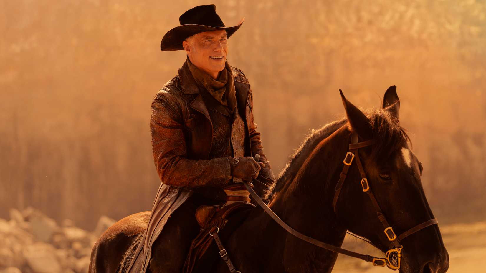 Captain Pike (Anson Mount) smiles while riding a horse dressed like a cowboy in Star Trek: Strange New Worlds season 4.