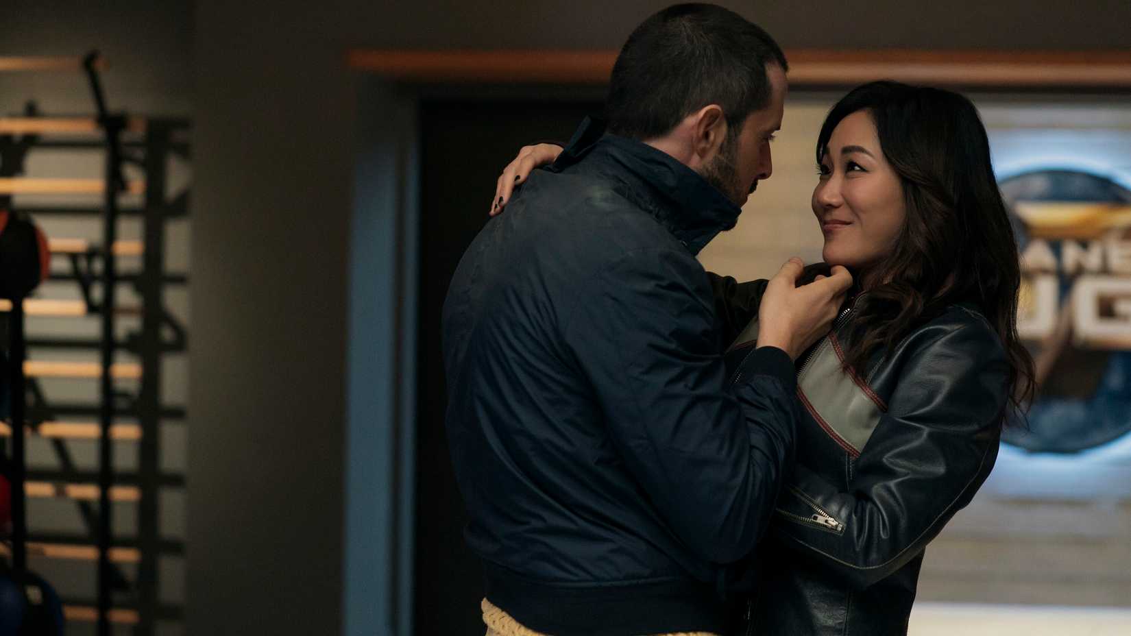 Frenchie (Tomer Capone) holds Kimiko (Karen Fukuhara) in his arms with a hand under her chin as she smiles in The Boys season 5.
