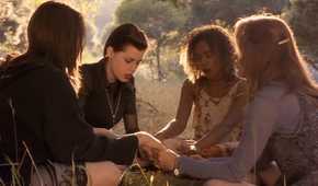 Four teen girls do witchcraft in a sunny field
