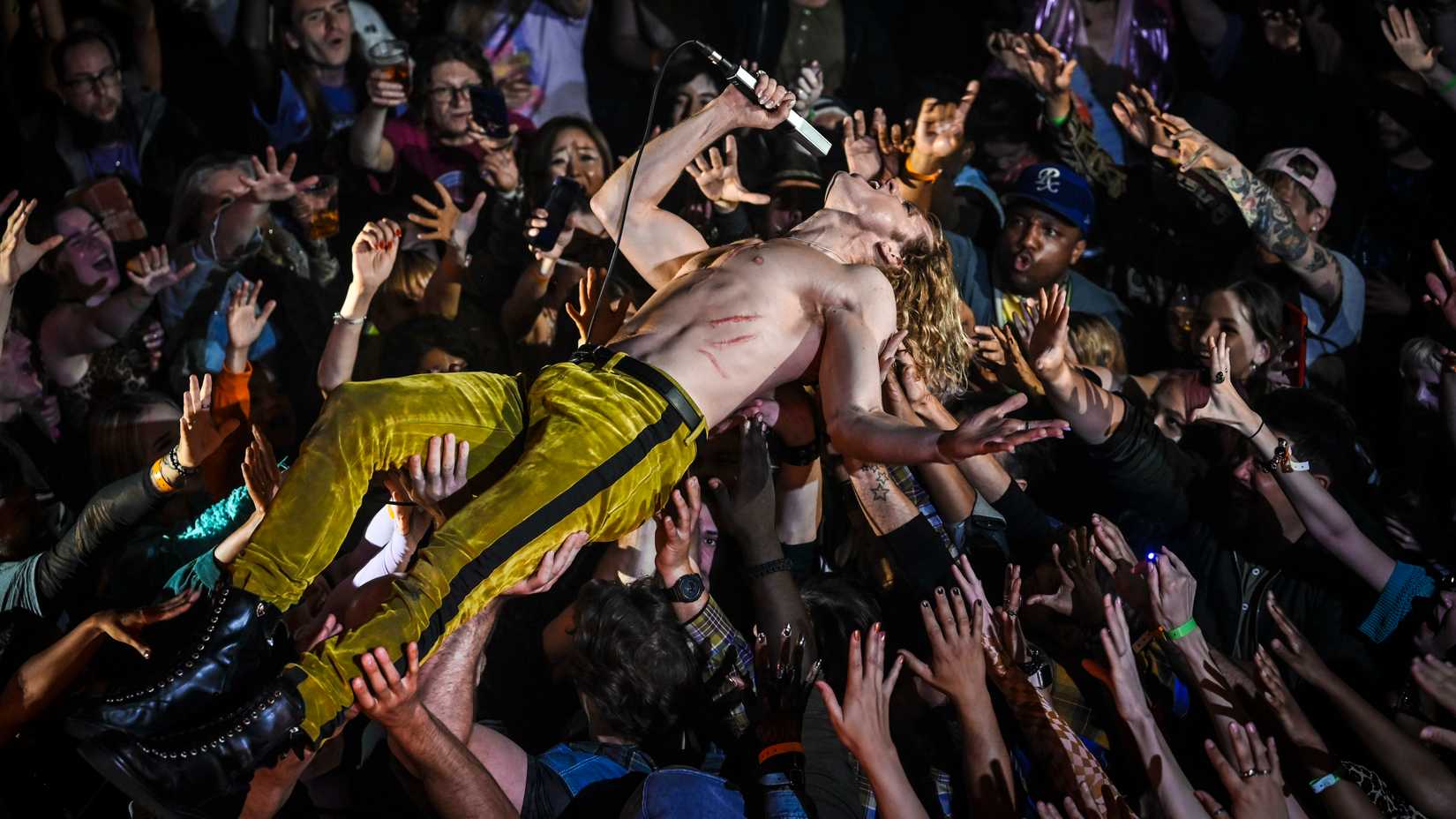 Lestat (Sam Reid) crowdsurfs while singing shirtless in The Vampire Lestat