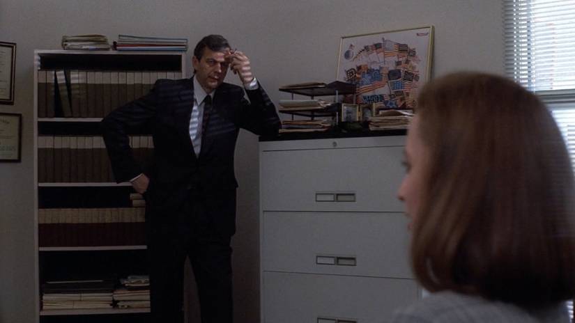 The Cigarette Smoking Man leans on a filing cabinet