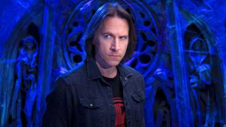 An image featuring Matthew Mercer from Critical Role. He stands against a blue, church-like background.