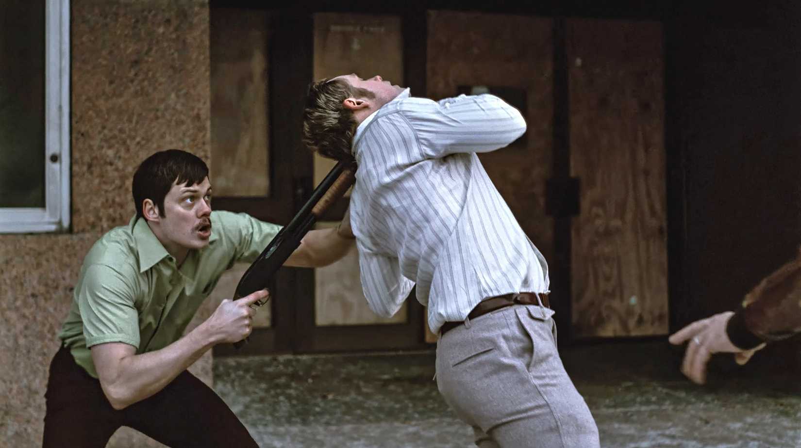 Bill Skarsgard holds a shotgun to Dacre Montgomery's head as he twists around