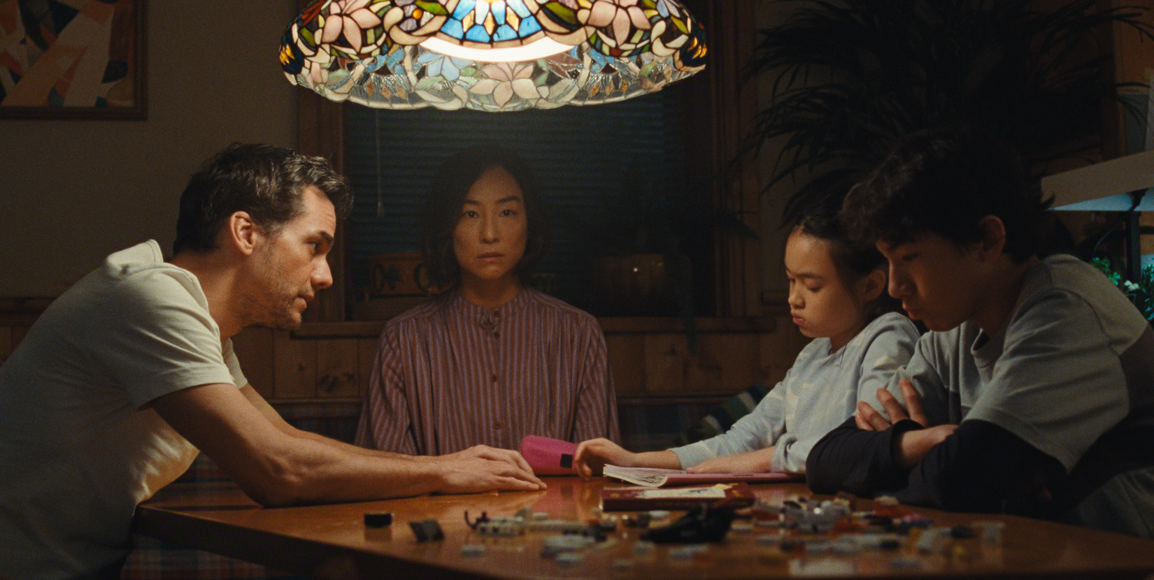 A screenshot from The Last House, a film from Netflix. A family of four sit at a table together.