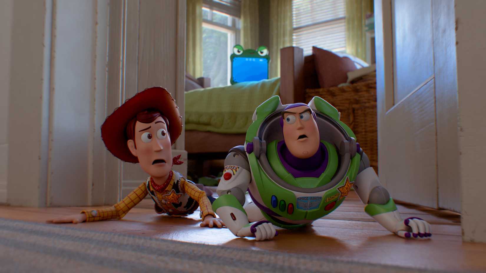 Woody and Buzz crawl on the floor of Bonnie's bedroom while Lilypad glares at them from the bed in Toy Story 5.