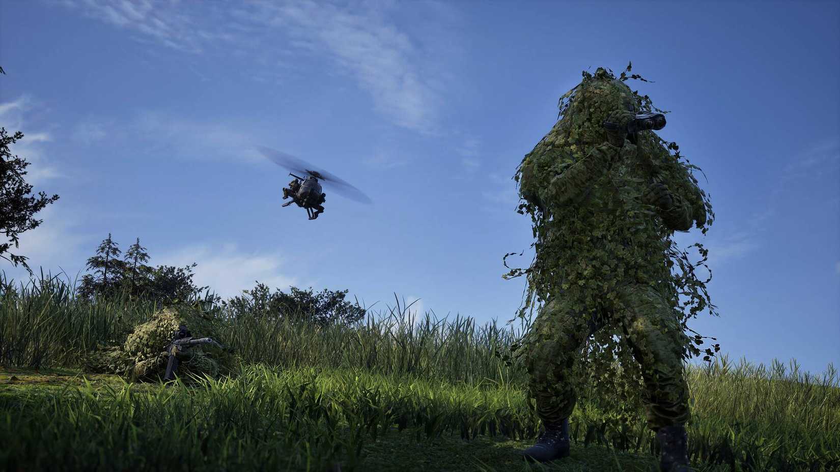 Two soldiers in ghillie suits in a field while a helicopter flies above them in Wardogs.