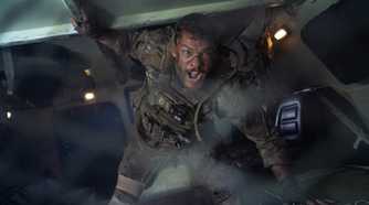 81 (Alan Ritchson) shouts inside an armored transport in a still from Netflix's War Machine