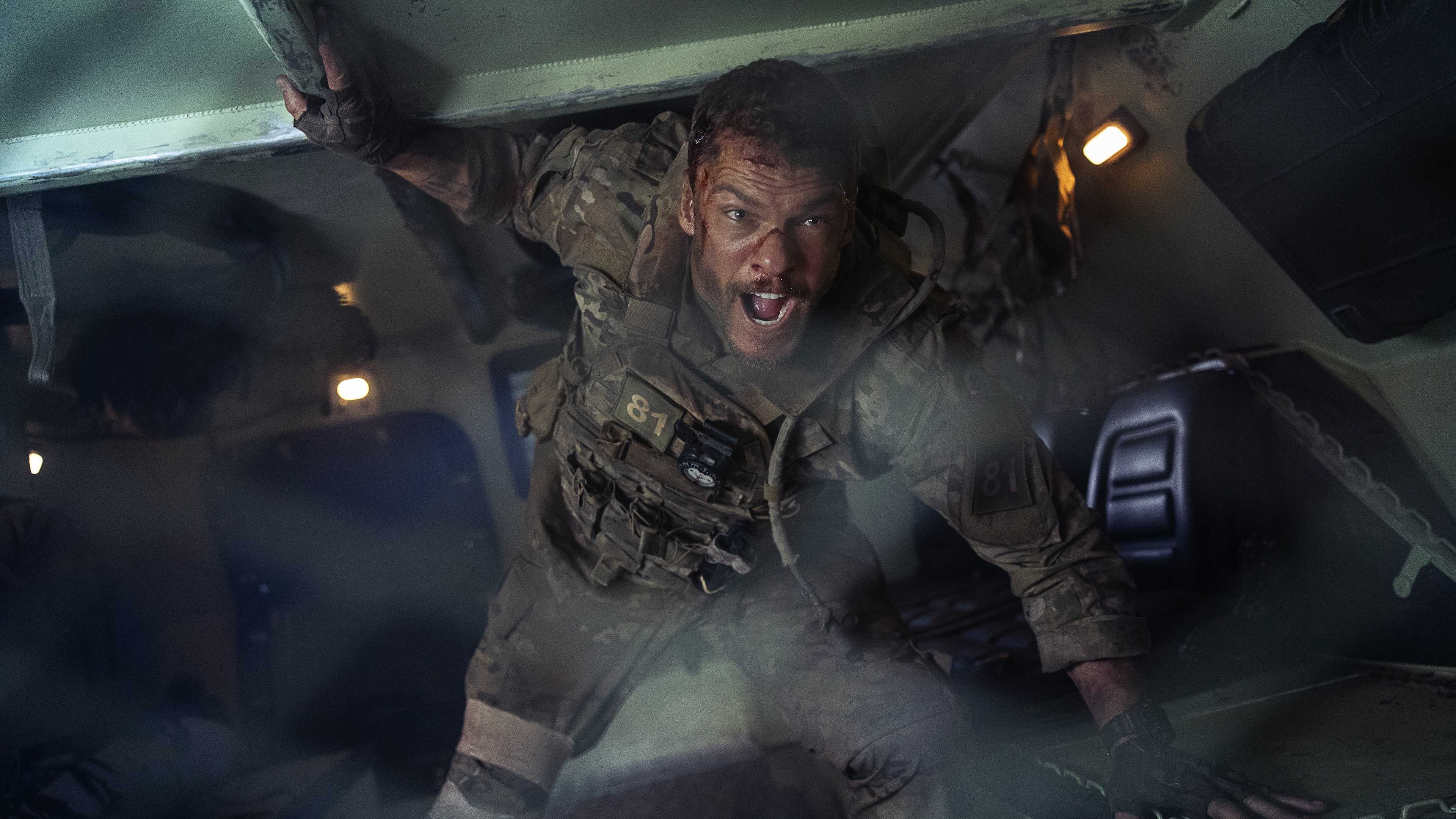 81 (Alan Ritchson) shouts inside an armored transport in a still from Netflix's War Machine