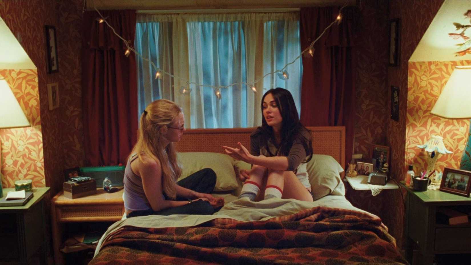Needy and Jennifer sit together on Needy's bed