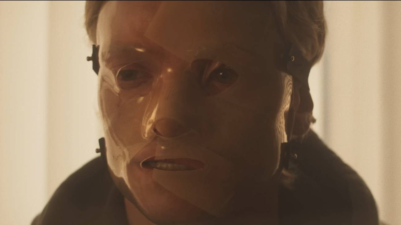 A man in a haunting, partially translucent mask.