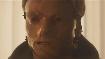 A man in a haunting, partially translucent mask.