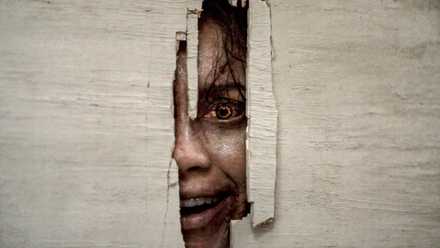 A deadite peeking through the door in Evil Dead Burn