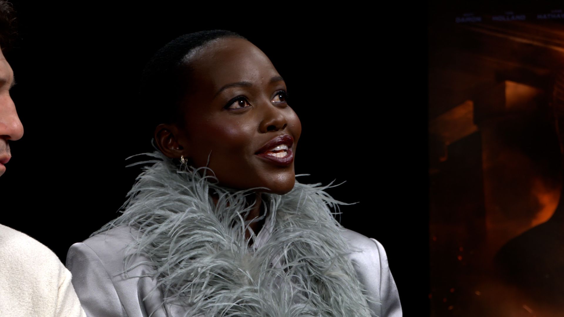 Lupita Nyong'o looks up and smiles