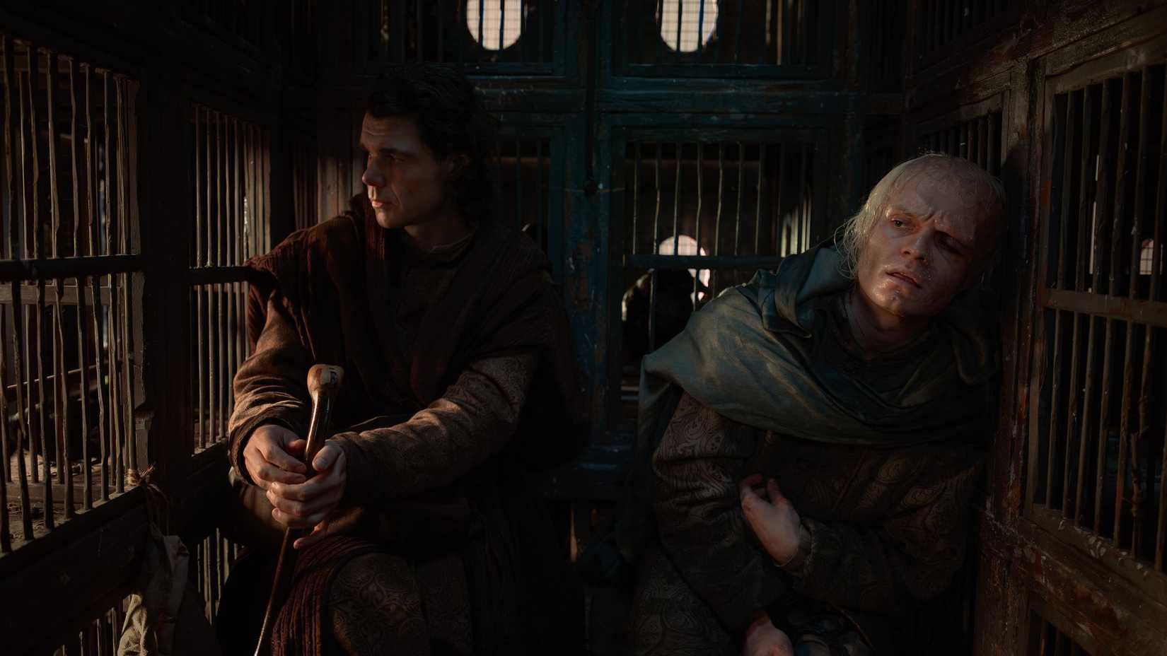 Larys Strong (Matthew Needham) and King Aemond (Tom Glynn-Carney) sit in the back of a carriage filled with bird cages i