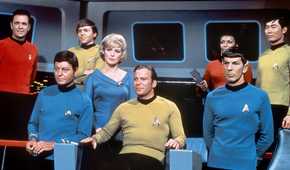 William Shatner as Kirk in his captain's char alongside the rest of the The Original Series' crew.
