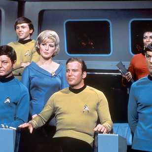 William Shatner as Kirk in his captain's char alongside the rest of the The Original Series' crew.
