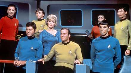 William Shatner as Kirk in his captain's char alongside the rest of the The Original Series' crew.