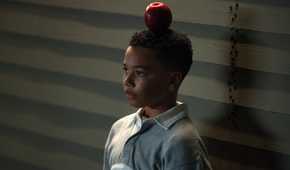 A young John Stewart (Cairo Cash Lee) stands with an apple balanced on his head in Lanterns