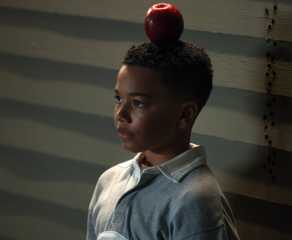 A young John Stewart (Cairo Cash Lee) stands with an apple balanced on his head in Lanterns