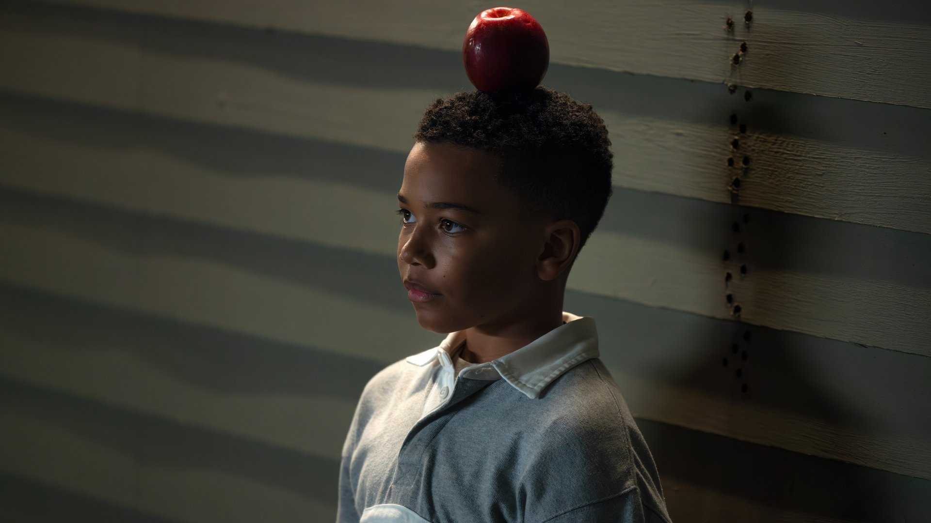 A young John Stewart (Cairo Cash Lee) stands with an apple balanced on his head in Lanterns
