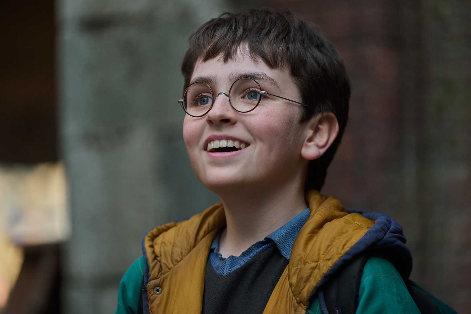 Dominic McLaughlin as Harry Potter in the HBO show smiling with his glasses on
