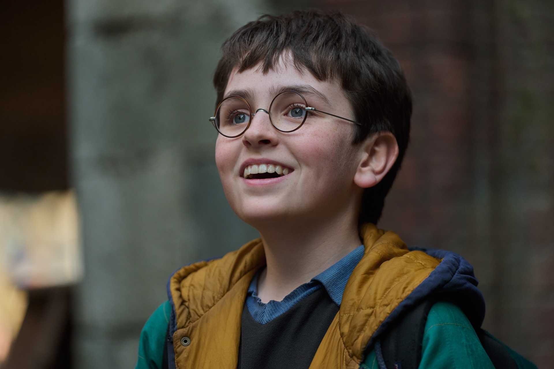 Dominic McLaughlin as Harry Potter in the HBO show smiling with his glasses on