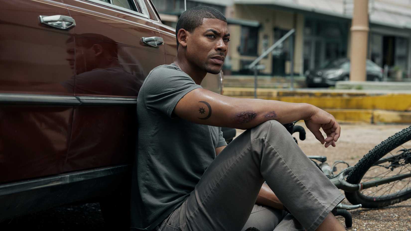 Terry Richmond (Aaron Pierre) crouches behind a car in Rebel Ridge