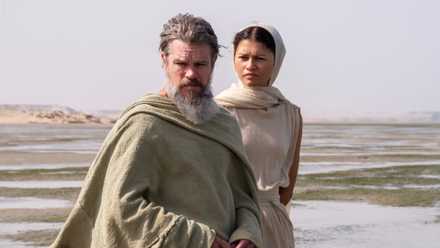 A gray-bearded Odysseus standing next to Athena on a beach.