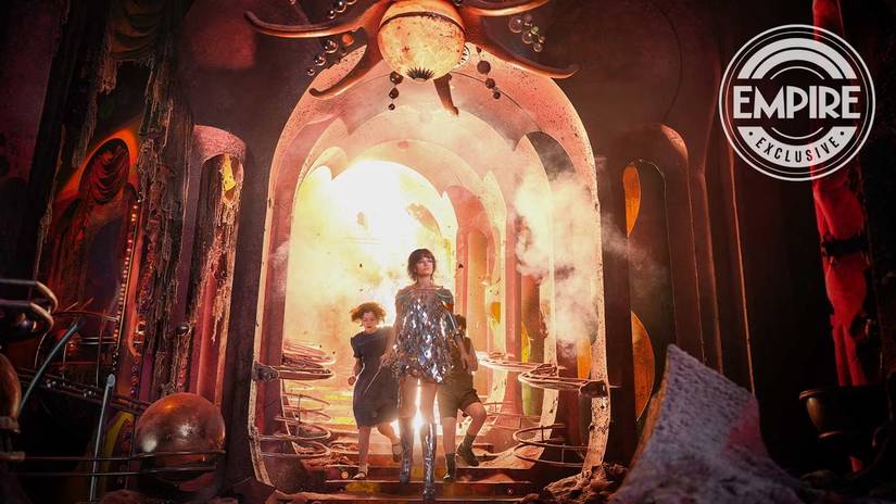 A woman in a glittery dress with two children walking away from an explosion.