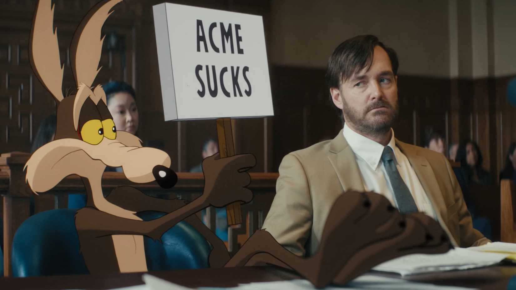 Wile E. Coyote holding up a sign that says Acme Sucks while his lawyer looks on with annoyance.