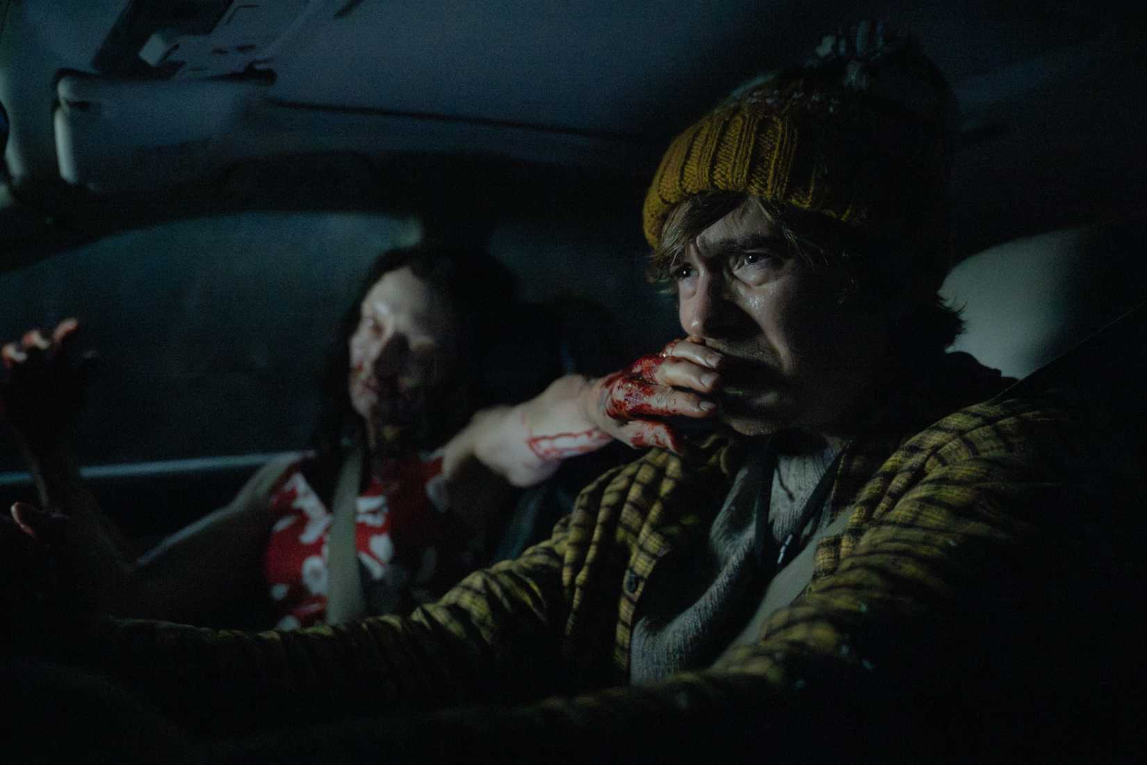 Austin Abrams gets a zombie hand stuck in his face while driving a car in Resident Evil