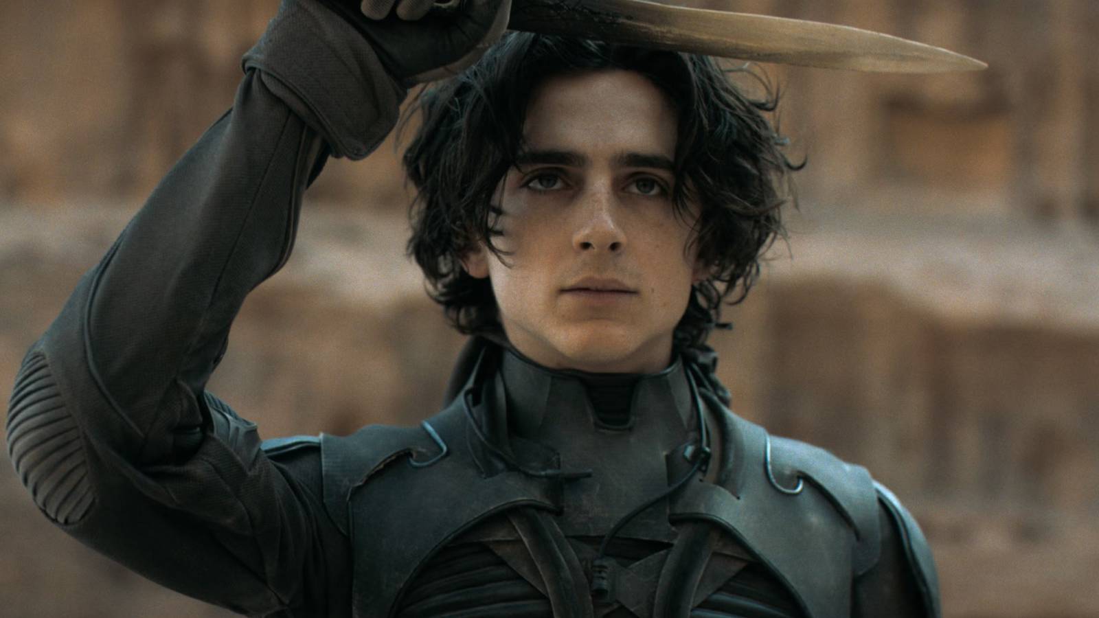 Timothée Chalamet salutes with a crysknife in the film Dune.