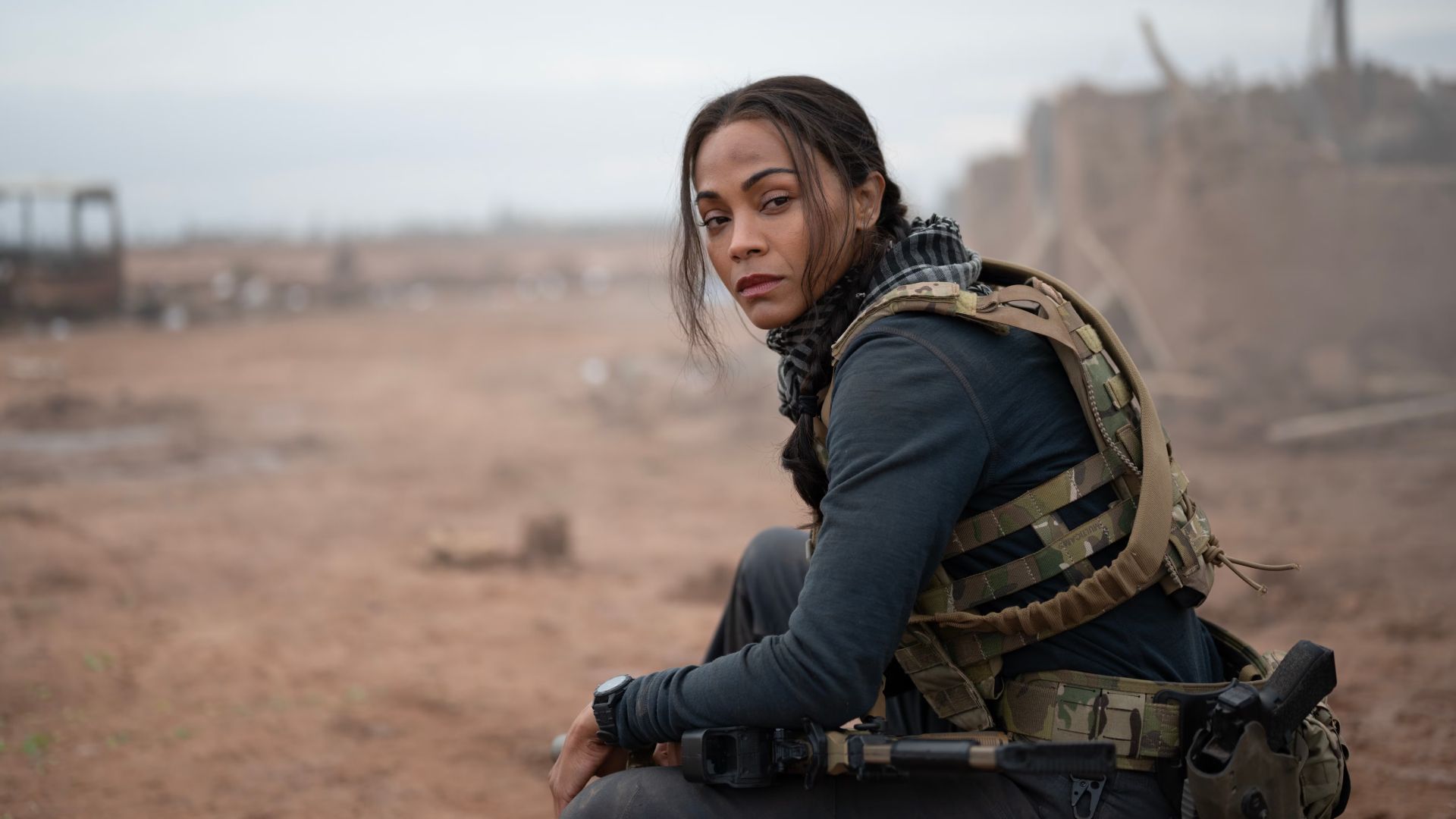 Zoe Saldaña sits in full combat gear on the edge of a battlefield in the Paramount Plus series Special Ops: Lioness.